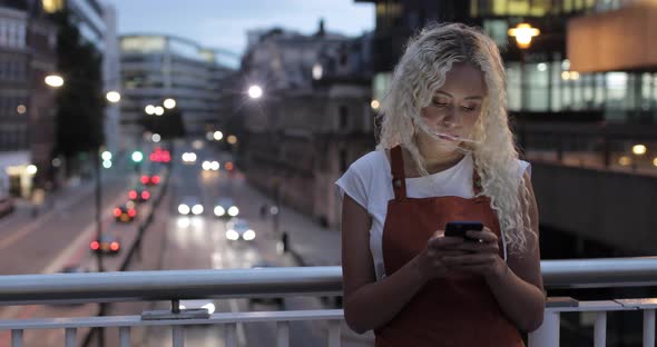 Pretty young woman typing message on smartphone, London, UK