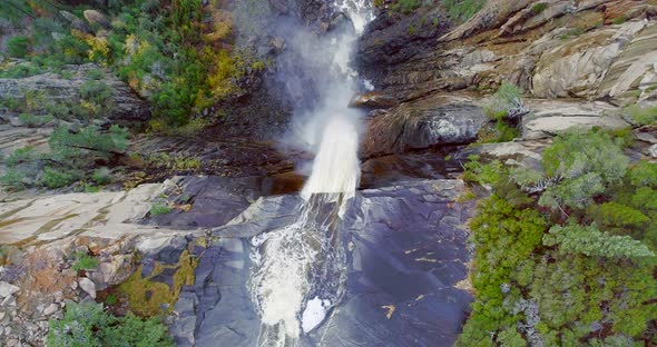 Aerial Top Shot of a Sheer Rock Granite with White Waterfall Along.