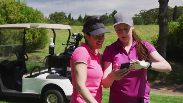 Two caucasian women playing golf using a smartphone