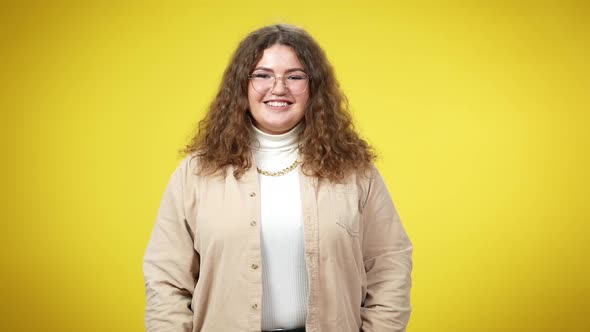 Medium Shot Portrait of Cheerful Overweight Young Caucasian Woman Posing at Yellow Background