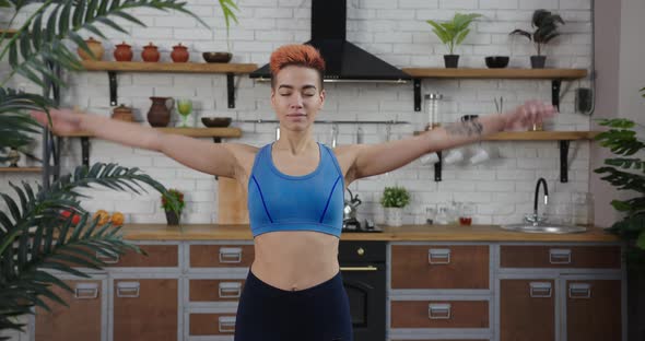 Woman with Colorful Haircut Does Yoga Asana in Kitchen