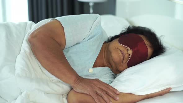 senior woman with eye mask sleeping on a bed in bedroom