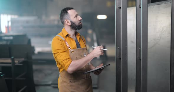 Worker Checking the Quality of Metal Products with a Digital Tablet