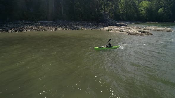 Aerial Of Bearded Man In Kayak Paddling Ocean Coastline alt