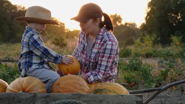 Mom and Little Son Talking Near a Full Pumpkin Cart