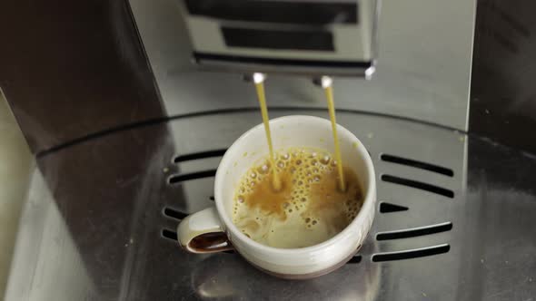 Espresso Shot Pouring Out From Coffee Machine in Small White and Brown Cup. Close Up Footage