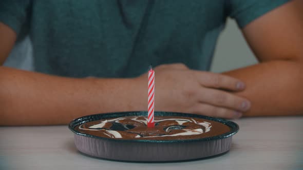 Man Is Blowing Out a Candle on a Cake