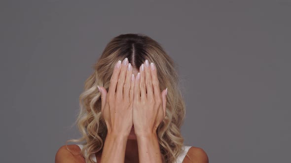 Studio portrait of young and beautiful blond woman over grey background.