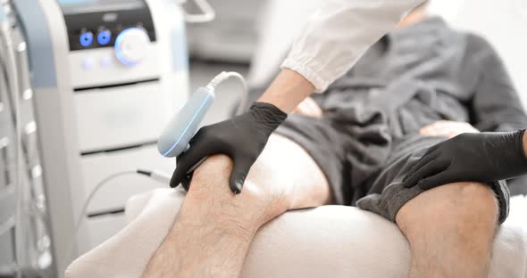 Doctor Doing Magnetic Therapy on Male Knee