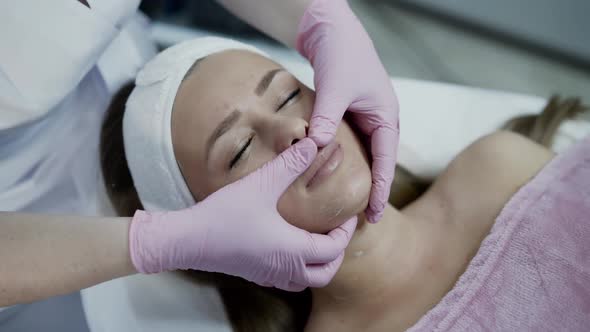 Close View of Beautician Hands Scrub Female Face with Mask in Cosmetology Clinic