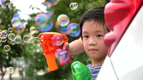 Cute Asian Child Shooting Bubbles From Bubble Gun