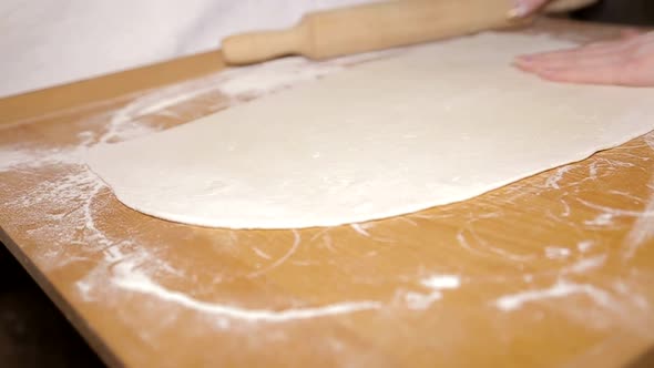 Woman molds dough at home. Roll out the dough with a rolling pin