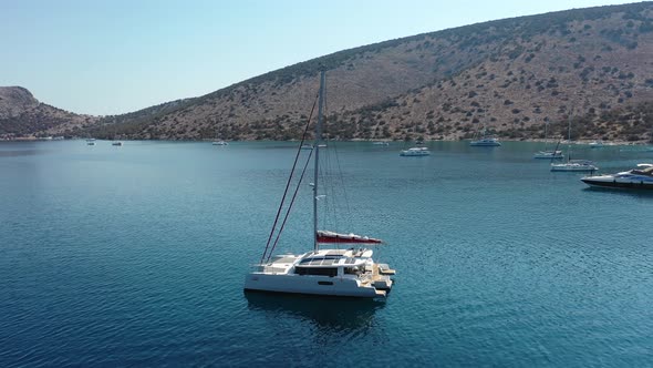 Catamaran and Sail Yachts Anchored at Bay on Deep Blue Sea Water on Sunrise