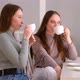 Two young women in cafe drinking coffee and chatting - VideoHive Item for Sale