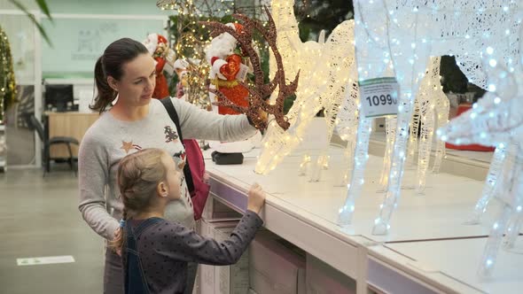 Little Girl with Mom Choosing LED Xmas Deer