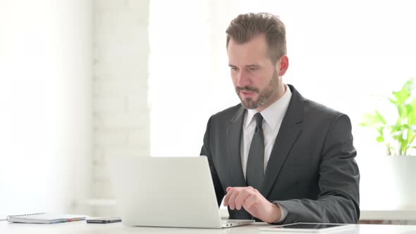 Young Businessman Celebrating Success While Using Laptop in Office