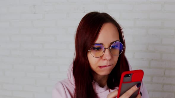 Young Woman Using Smartphone Near Wall