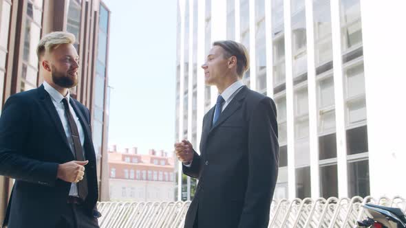 Confident businessman and his colleague in front of modern office building.