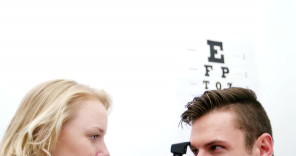 Optometrist examining female patient through ophthalmoscope