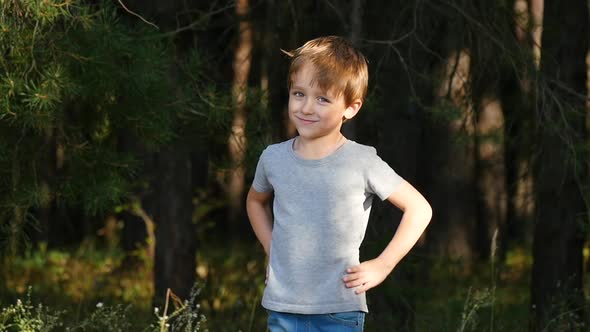 A Cute Little Boy Smiles As He Looks at the Camera and Keeps His Hands on His Belt. Portrait