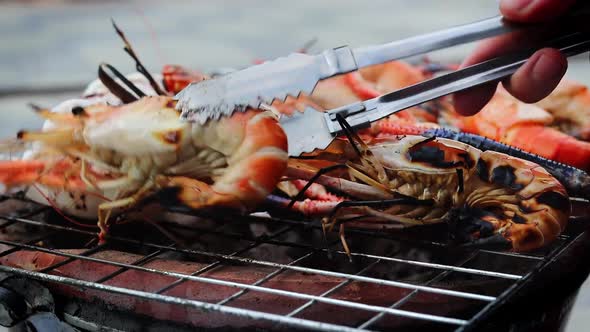 a side view of grilled shrimps that are being turned by a thai girl, Thailand.