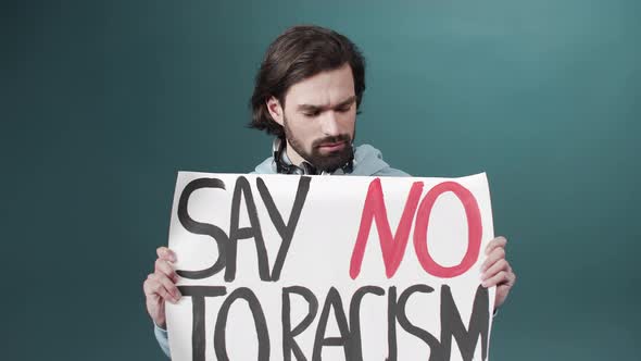 An Adult White Man in a Blue Hoodie is Raising a Poster Against Racism in Slow Motion