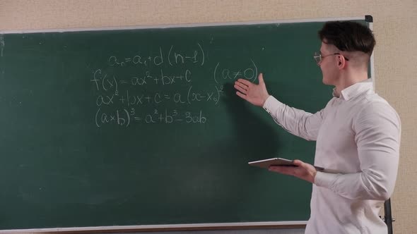 Portrait of a Young Student in Glasses with a Tablet Near the Blackboard