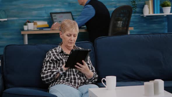 Middle Aged Old Woman Relaxing Holding Tablet Reading e Book