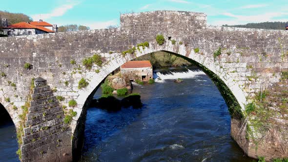 Aerial View Of Old Water Mill With Dolly Back Through Old Medieval Bridge Over River Tambre. Pedesta