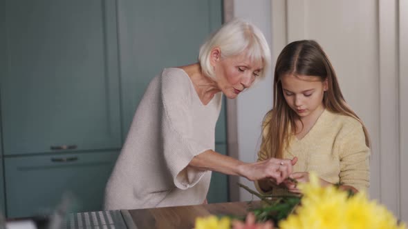 Concentrated girl with grandmother trimming the ends of flowers