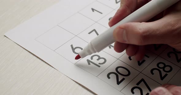 Man's Hand Write Down the 6Th Day on the Paper Calendar Using a Red Pen