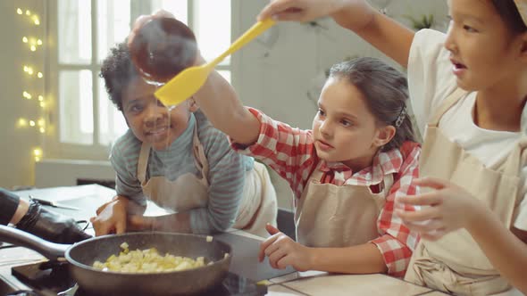 Kids Adding Honey to Fruit in Pan during Cooking Class