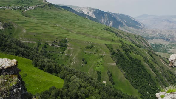 Top view of rocky cliffs above green mountain valley