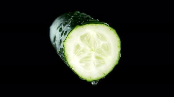 Half of Tasty Broken Cucumber with Water Drops on Black