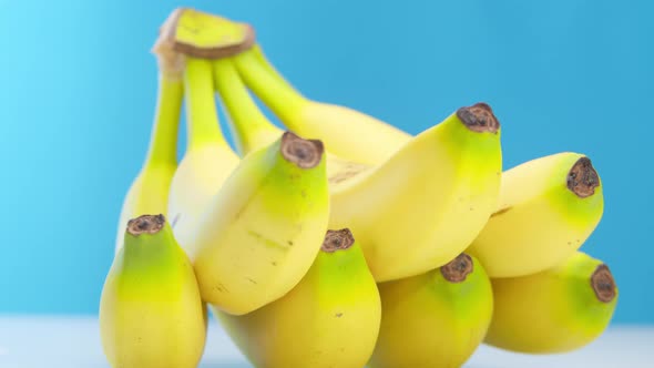 Beautiful Ripe Yellow Bananas with Drops of Freshness Lie on the Table on a Blue Background