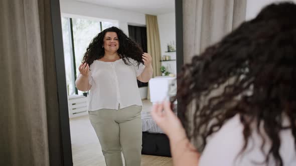 Young Overweight Woman Looks at Reflection and Enjoys Life