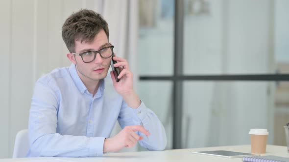 Young Man Talking on Phone in Office
