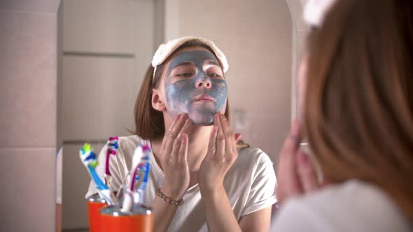 A Young Woman Washes Off a Grey Mask From the Face