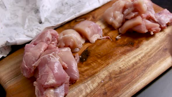 Woman's hands cut fresh chicken pieces on a wooden board close up