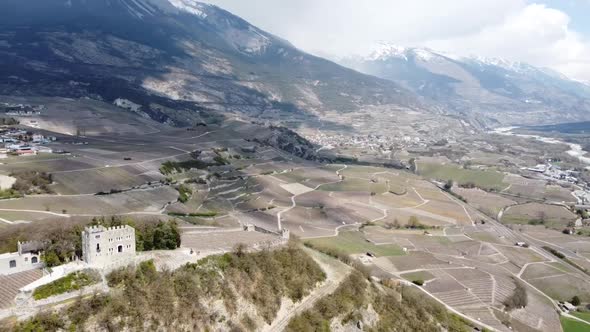 tiny castle in the middle of a green valley in switzerland (Sierre, Valais), with shadows of the clo