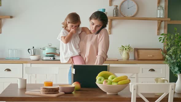 A Busy Mother Trying to Work Remotely While Holding Her Crying A Little Daughter