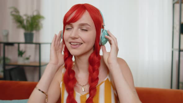 Happy Young Redhead Girl in Wireless Headphones Dancing Singing Listening Favorite Song at Home Room