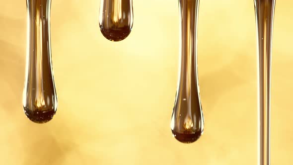 Super Slow Motion Macro Shot of Dripping Oil on Golden Background at 1000 Fps