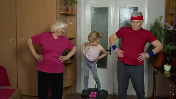 Granddaughter and Mature Grandparents in Sportswear Making Sports Jogging Workout Exercises at Home