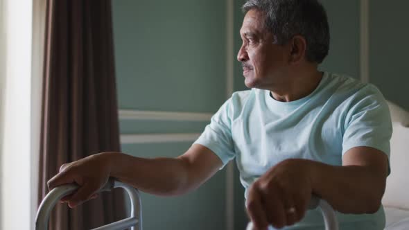 Senior mixed race man with walking frame looking out of window