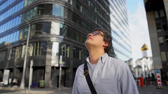 Pan Shot of Man Standing in the Center of the Road Looking at the Buildings