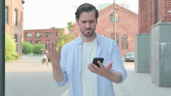 Man Having Loss on Phone While Walking in Street