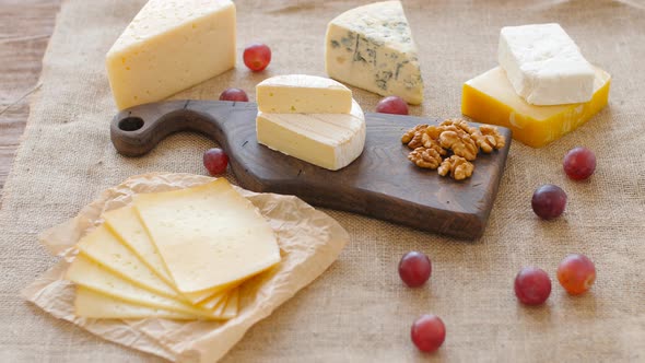 Cheese Platter with Nuts and Grapes on a Wooden Cutting Board