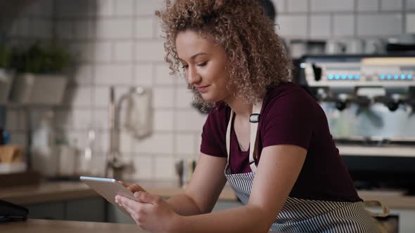 Young caucasian waitress using digital tablet in the cafe. Shot with RED helium camera in 8K.