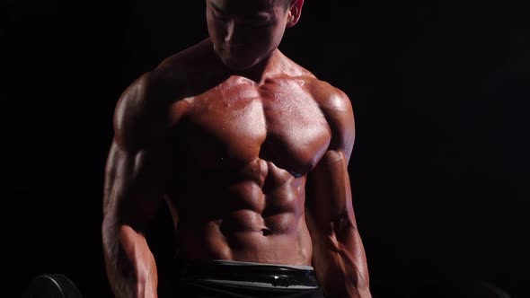 Asian Bodybuilder Training Biceps in Gym. Black Background